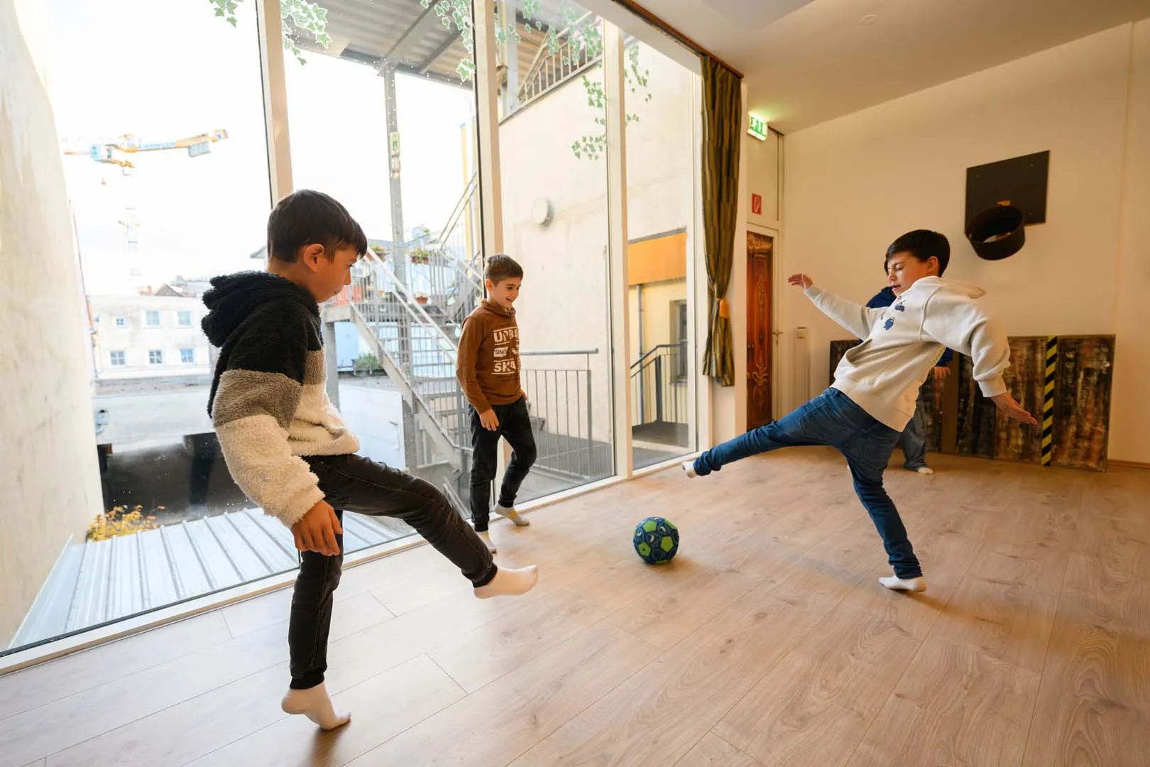 Am Bild zu sehen sind 3 Kinder, die gerade in der Kinderranch im Kleinstadtbiotop Vöcklabruck Fußball spielen